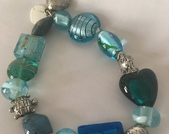 Pulsera elástica vintage de Avon con cuentas de vidrio, diseño de corazón, tortuga, pez y concha de almeja.