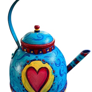 May include: A blue teapot with a red heart painted on the front. The teapot has a yellow rim and a red and yellow striped spout.