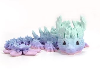 May include: A pastel blue and purple dragon figurine with a floral design. The dragon is made of a soft, pliable material and has a whimsical, fairytale-like appearance.