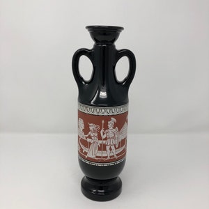 May include: Black ceramic vase with two handles and a red and white design featuring a scene of Greek mythology.