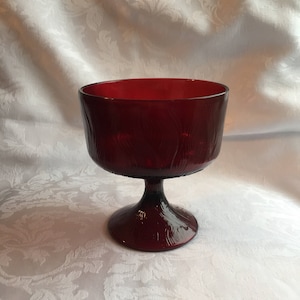 May include: A deep red glass bowl with a textured surface and a flared base. The bowl is on a white background.