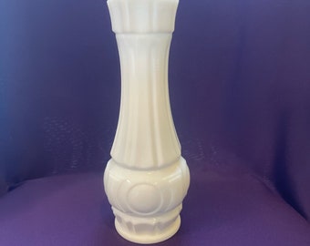 May include: A white milk glass vase with a fluted design and a circular pattern around the base.