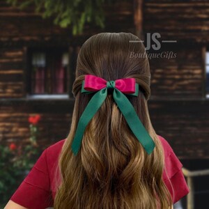 Pode incluir: Um prendedor de cabelo de fita de cetim verde e rosa. O la&ccedil;o &eacute; amarrado em um estilo cl&aacute;ssico com caudas longas. O prendedor de cabelo &eacute; perfeito para adicionar um toque de eleg&acirc;ncia a qualquer penteado.