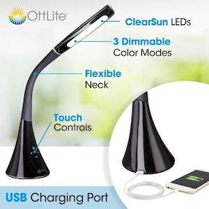 May include: A black OttLite desk lamp with a flexible neck, touch controls, and ClearSun LEDs. The lamp features three dimmable color modes and a USB charging port. A circular inset shows the base of the lamp connected to a white charging cable.