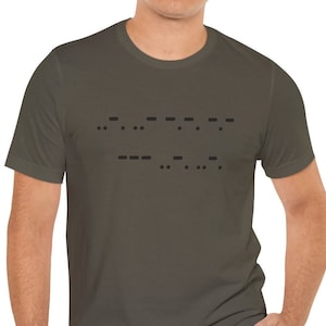 May include: A dark gray t-shirt with black Morse code text across the chest. The shirt is a solid color and has short sleeves. The Morse code appears to spell out a word or phrase.