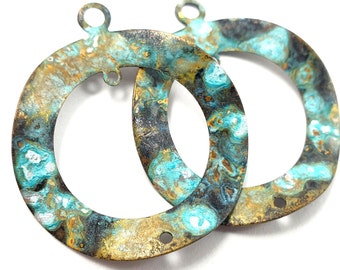 May include: Two round metal charms with a turquoise, gold, and black marbled finish. The charms have a hole at the top for hanging and two smaller holes on the side.