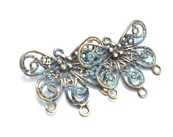 May include: Two antique gold butterfly charms with intricate filigree details and a blue patina finish. Each charm has three loops for attaching to jewelry or other crafts.