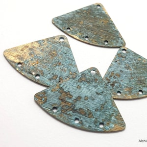 Puede incluir: Cuatro formas triangulares de metal con un acabado desgastado, envejecido, azul y dorado. Cada triángulo tiene cinco agujeros alrededor del borde.