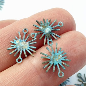 May include: Four turquoise blue metal starburst charms with a loop at the top. The charms have a distressed finish and are perfect for jewelry making.