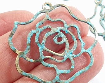 May include: A turquoise and gold metal rose charm with a cutout design. The charm has a loop at the top for attaching to jewelry or other crafts.