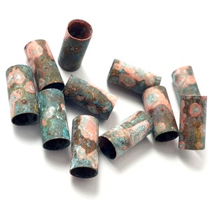 May include: A group of ten copper tubes with a green and orange patina finish. The tubes are arranged in a random pattern on a white surface.