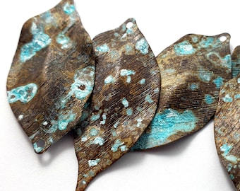 May include: Five metal leaf-shaped charms with a distressed, aged finish. The charms are a mix of brown and turquoise blue.