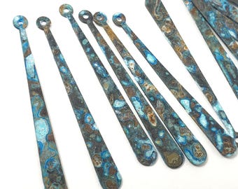 May include: A set of ten long, thin, metallic, blue and brown patterned, teardrop-shaped charms with a small hole at the top.