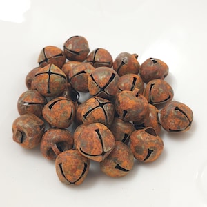 Könnte beinhalten: Ein Haufen rostiger Metall-Glöckchen. Die Glöckchen sind tief orangefarben mit einer braunen Patina.