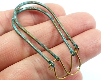 Può includere: Un paio di orecchini a cerchio in turchese e ottone. I cerchi sono realizzati in filo sottile e hanno una finitura leggermente martellata. Gli orecchini sono semplici ed eleganti.