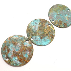 May include: Three round metal charms with a distressed, aged finish. The charms are a mix of turquoise, brown, and gold colors. Each charm has two holes for attaching to jewelry or other crafts.