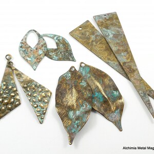 May include: Assortment of metal jewelry findings in various shapes and sizes. The findings are made of brass and have a distressed, aged finish with shades of gold, green, and brown.