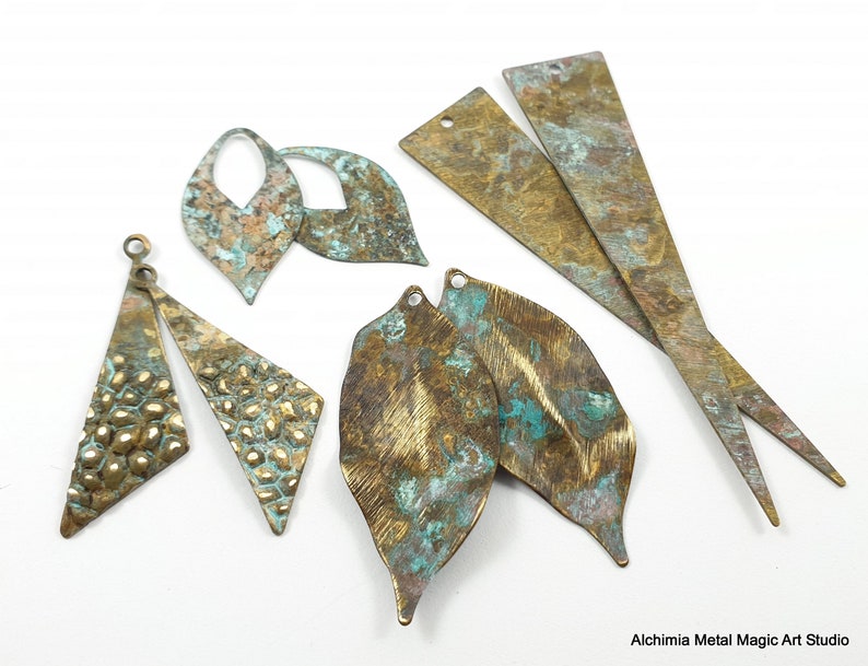 May include: Assortment of metal jewelry findings in various shapes and sizes. The findings are made of brass and have a distressed, aged finish with shades of gold, green, and brown.