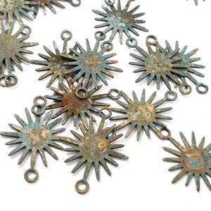 May include: A group of 10 rustic, antique-looking metal starburst charms with a distressed, aged finish. Each charm has a loop at the top for attaching to jewelry or other crafts.