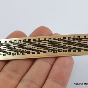 Peut inclure: Une bande de métal doré avec un motif tissé noir gravé à la surface. La bande mesure environ 7,6 cm de long et 2,5 cm de large.