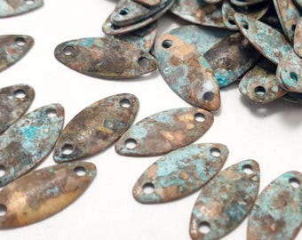 May include: A pile of oval-shaped metal charms with a distressed, aged finish. The charms are a mix of brown, copper, and turquoise colors. Each charm has two holes for attaching to jewelry or other crafts.