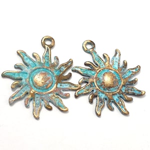 May include: Two antique gold sun charm pendants with a turquoise patina finish. The sun charms have a raised center and a textured surface.