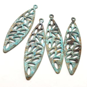 May include: Four turquoise and brown metal leaf-shaped charms with a cut-out design. The charms have a hole at the top for attaching to jewelry.