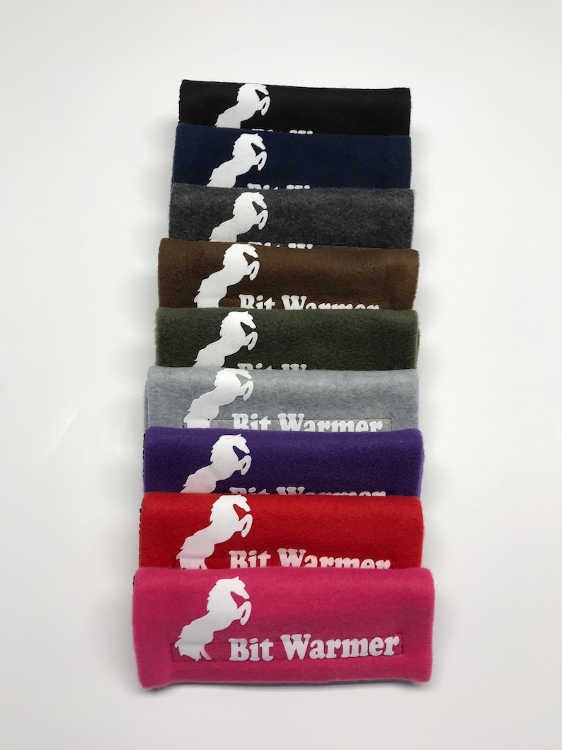 May include: A stack of ten fleece horse bit warmers in various colours, including black, navy blue, grey, brown, green, purple, red, and pink. Each warmer features a white horse silhouette and the text "Bit Warmer".