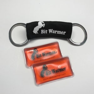 May include: Two orange gel packs with a black horse logo and the text "Bit Warmer" and "www.abitwarmer.com". A black fabric bit warmer with a white horse logo and the text "Bit Warmer" is attached to a silver double ring.