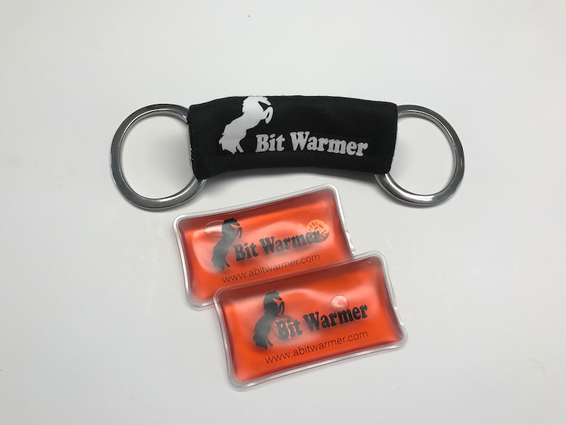 May include: Two orange gel packs with a black horse logo and the text "Bit Warmer" and "www.abitwarmer.com". A black fabric bit warmer with a white horse logo and the text "Bit Warmer" is attached to a silver double ring.