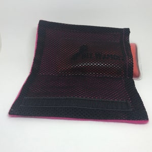 May include: A pink mesh pouch with a black velcro strap. The pouch is designed to hold a hot or cold pack.