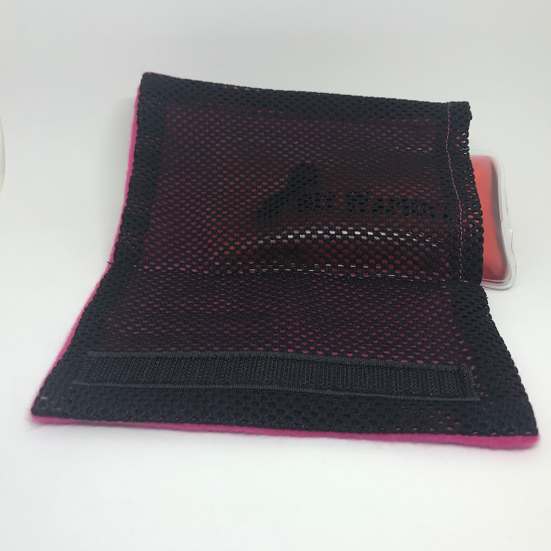 May include: A pink mesh pouch with a black velcro strap. The pouch is designed to hold a hot or cold pack.