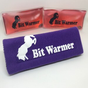 May include: Two pink gel packs with the text "Bit Warmer" and a white horse logo. A purple fleece strap with the text "Bit Warmer" and a white horse logo.
