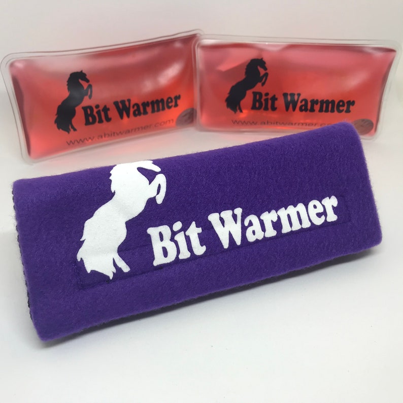 May include: Two pink gel packs with the text "Bit Warmer" and a white horse logo. A purple fleece strap with the text "Bit Warmer" and a white horse logo.