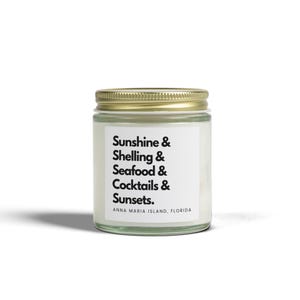 Peut inclure: Un pot à bougie en verre transparent avec un couvercle en métal doré et une étiquette blanche portant le texte noir : Sunshine & Shelling & Seafood & Cocktails & Sunsets. ANNA MARIA ISLAND, FLORIDA. La cire à l'intérieur est blanche.