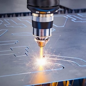 May include: A close-up of a laser cutting machine cutting a metal sheet. The laser beam is visible as a bright orange light, and sparks are flying off the metal.