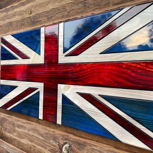 May include: A wooden Union Jack flag with red, white, and blue paint. The flag is made of wood and has a glossy finish.