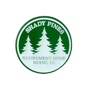 Puede incluir: Un pin circular verde y blanco con el texto "Shady Pines Retirement Home Miami, FL" y tres pinos blancos.