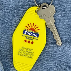 May include: Yellow motel key tag with a sun and the text "Solana All-Inclusive Resort Benidorm" and "YOU DON'T NEED MONEY, THIS HOLIDAY IS INCONCLUSIVE".