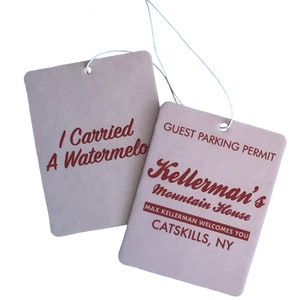 Könnte beinhalten: Zwei braune Papier-Auto-Lufterfrischer mit rotem Text. Der obere sagt "I Carried A Watermelo". Der untere sagt "GUEST PARKING PERMIT Kellerman's Mountain House MAX KELLERMAN WELCOMES YOU CATSKILLS, NY".