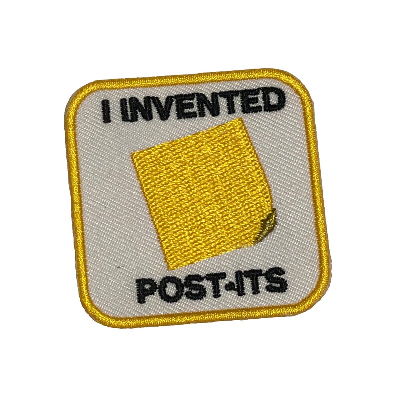 May include: A yellow embroidered patch with a white background and black text that reads "I invented Post-its". The patch features a yellow sticky note with a curled corner.