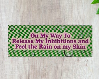 May include: A green and white checkered background with raindrops. The text "On My Way To Release My Inhibitions and Feel the Rain on My Skin" is written in purple.