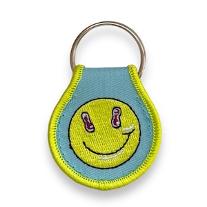 Llavero con parche de cara feliz diseñado por Puppyteeth