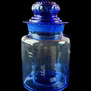 Peut inclure: Un bocal d'apothicaire en verre bleu cobalt avec un couvercle assorti. Le bocal a une base large et un corps cylindrique, avec un bord &eacute;vas&eacute; et un couvercle d&eacute;coratif et arrondi. Le verre est transparent.