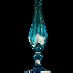 Pode incluir: Um vaso de vidro azul alto com uma base alargada e uma parte superior com babados. O vaso tem um design texturizado e facetado.