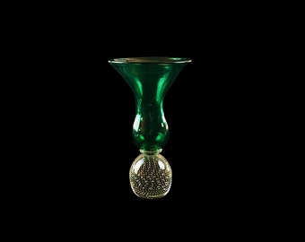 Peut inclure: Un vase en verre vert avec une base ronde en verre clair avec de petites bulles. Le vase a un sommet évasé et un col étroit.