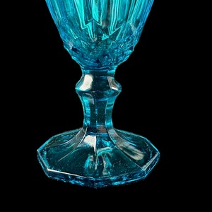 Pode incluir: Um copo de vidro azul turquesa com um design facetado e uma base larga e octogonal.