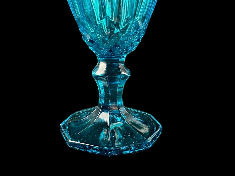 Pode incluir: Um copo de vidro azul turquesa com um design facetado e uma base larga e octogonal.
