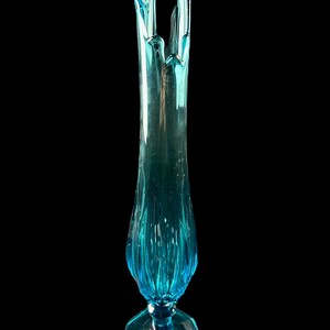 Pode incluir: Um vaso de vidro azul alto com um design ondulado &uacute;nico. O vaso tem uma base larga e alargada e um pesco&ccedil;o estreito.