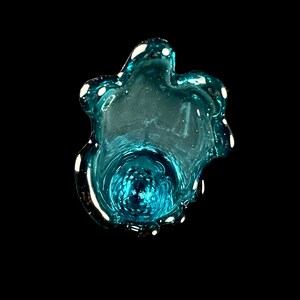 Pode incluir: Um vaso de vidro azul turquesa com uma forma org&acirc;nica &uacute;nica. O vaso tem uma abertura larga e uma base estreita.